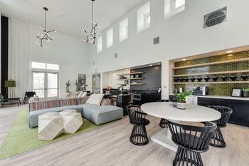Community clubhouse with round white table, black chairs, hardwood inspired floor